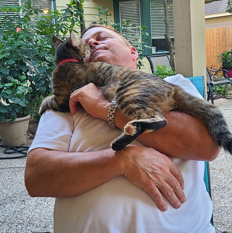 Nugget being held and kissed by her person in the backyard